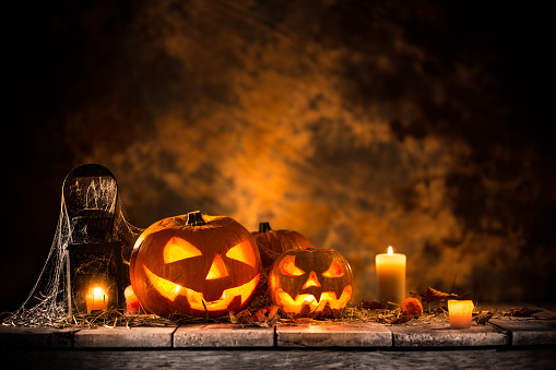 Halloween pumpkins on wooden planks with spooky background.