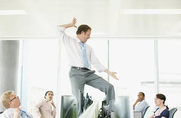 Photo of Businessman dancing on desk in cubicle