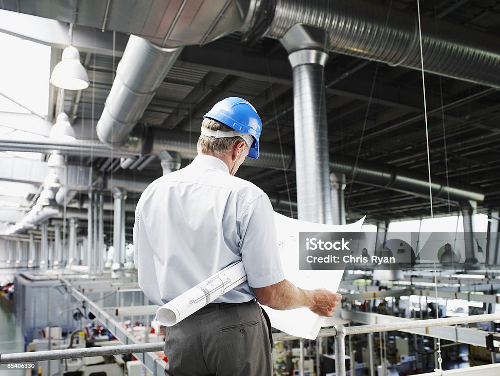 Hombre de negocios con duro sombrero mirando a blueprints - Foto de stock de 45-49 años libre de derechos