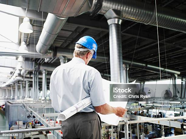 Hombre De Negocios Con Duro Sombrero Mirando A Blueprints Foto de stock y más banco de imágenes de 45-49 años