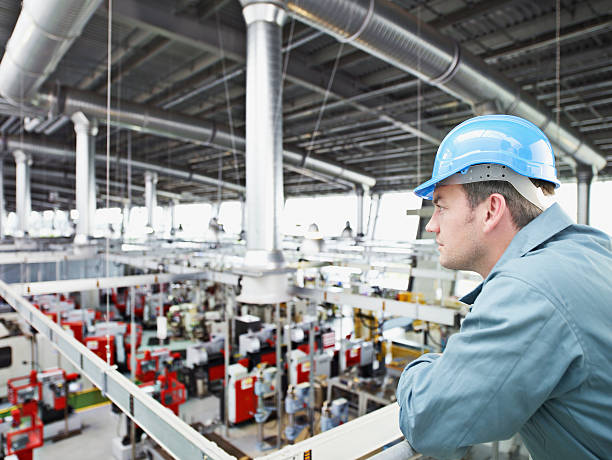 Factory-worker in hard-hat looking at factory floor  leaning stock pictures, royalty-free photos & images