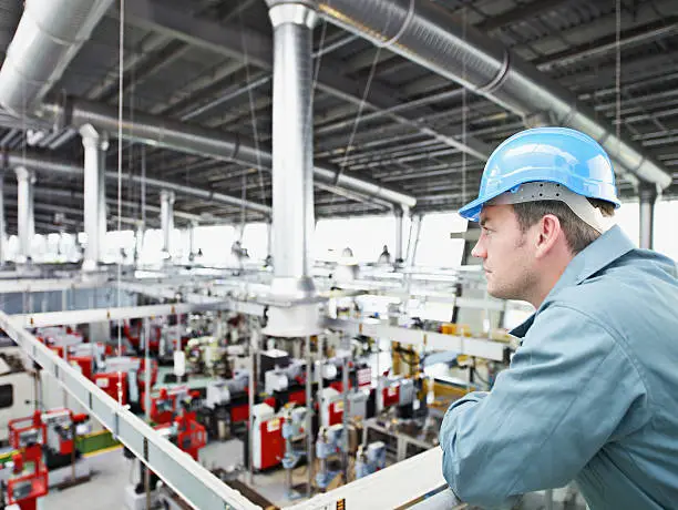 Photo of Factory-worker in hard-hat looking at factory floor