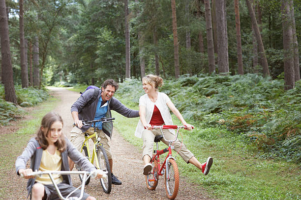 Family riding bicycles in woods  40 49 years stock pictures, royalty-free photos & images