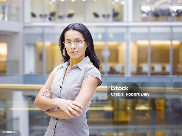 Geschäftsfrau Posieren Mit Arme Verschränkt Stockfoto und mehr Bilder von 25-29 Jahre - 25-29 Jahre, Arme verschränkt, Atrium - Architektonisches Detail