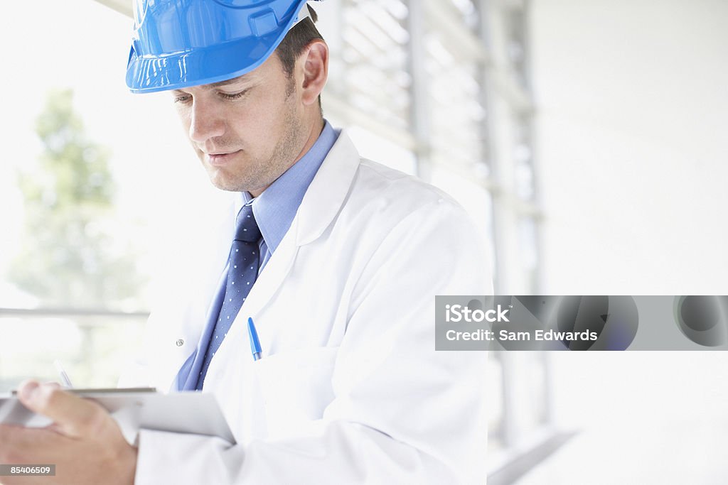 Businessman in hard-hat writing on clipboard  Hardhat Stock Photo