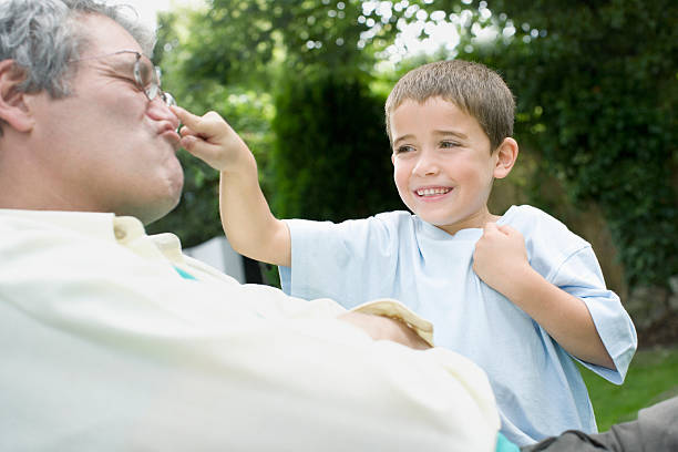 petit-fils jouer avec grandfathers nez - poking nose in photos et images de collection