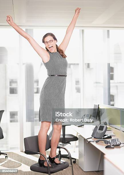 Businesswoman At Desk Cheering Stock Photo - Download Image Now - Chair, Standing, Celebration