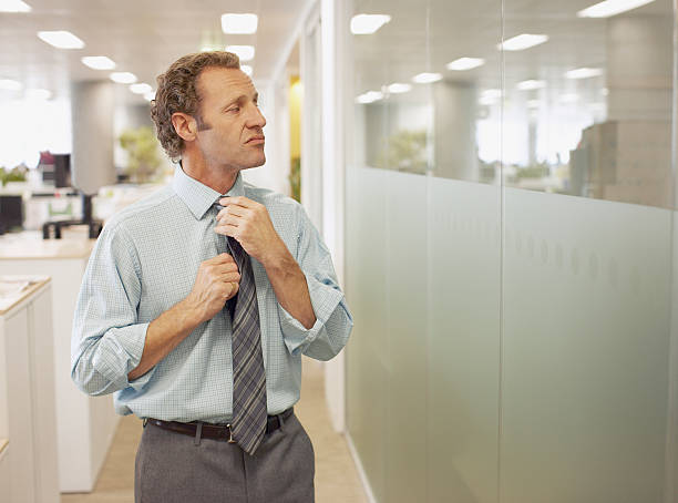 Businessman adjusting tie in office  man adjusting tie stock pictures, royalty-free photos & images