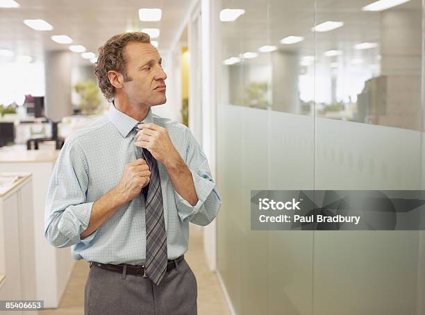Businessman Adjusting Tie In Office Stock Photo - Download Image Now - Vanity, Arrogance, Men