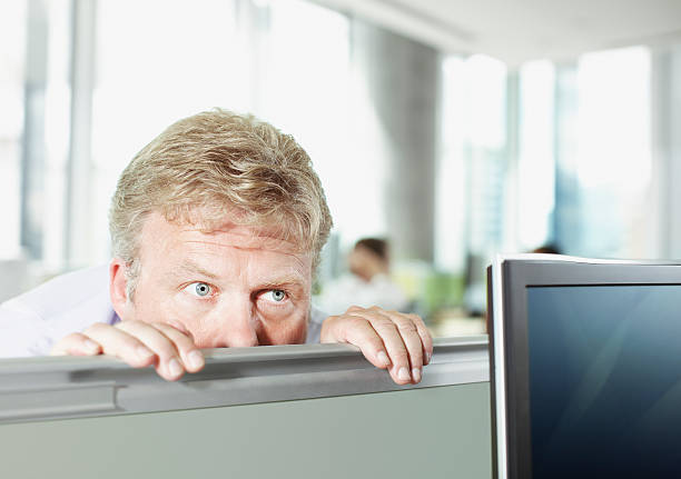 Businessman peering over cubicle wall  eavesdropping stock pictures, royalty-free photos & images