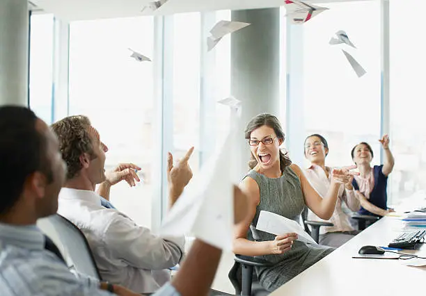 Photo of Businesspeople throwing paper airplanes in office