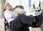 Businessman sleeping with feet up at desk