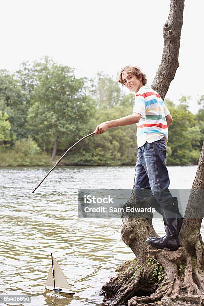 Niño Jugando Con Juguetes De Vela En El Lago Foto de stock y más banco de imágenes de Botas de agua - Botas de agua, 12-13 años, Actividad de fin de semana