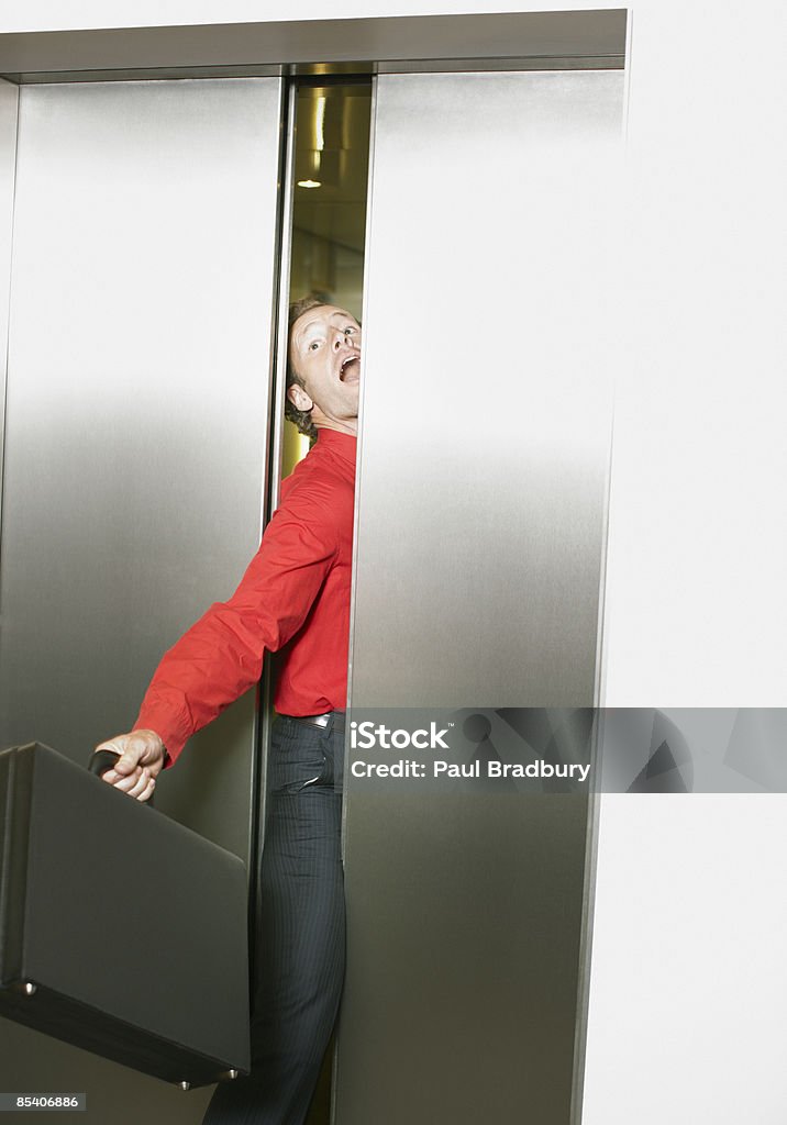 Businessman getting stuck in elevators doors  Elevator Stock Photo