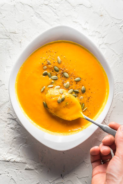 istock Pumpkin soup with seeds and a spoon with soup in hand 854078748