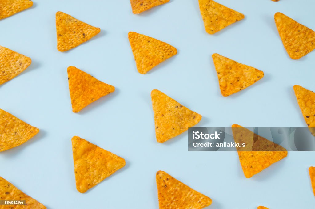 Pattern of Nachos Nachos chips laid out on a soft blue background. Potato Chip Stock Photo