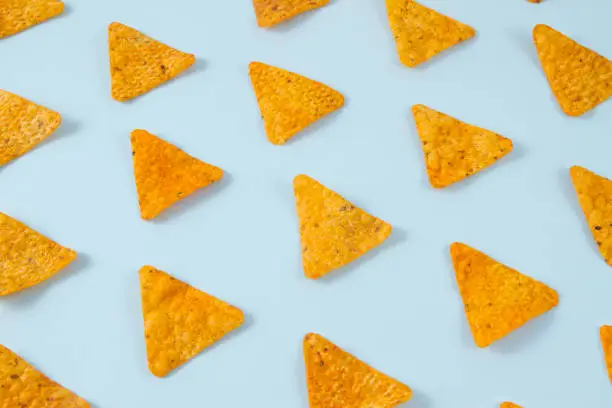 Nachos chips laid out on a soft blue background.