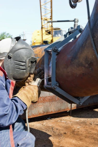 istock welder in coveralls makes a weld on a pipe of large diameter 854082952