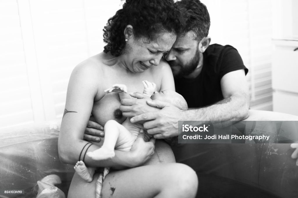 Home Birth Mother and father holding newborn immediately after home birth in pool. Home Birth Stock Photo