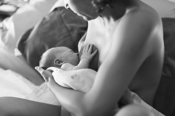 Breastfeeding Mother breastfeeding newborn for the first time after home birth. water birth stock pictures, royalty-free photos & images