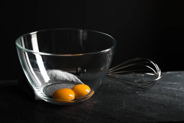 istock Chicken yolks in a bowl and whisk for beating on a gray table 854114290