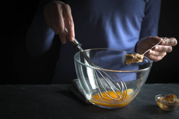 istock Whipped yolks, spoon in hand with mustard on purple background 854114640