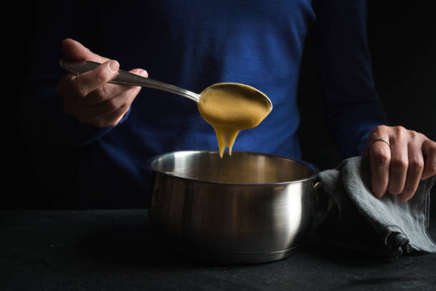 istock Spoon in hand with base sauce roux on blue background side view 854124556