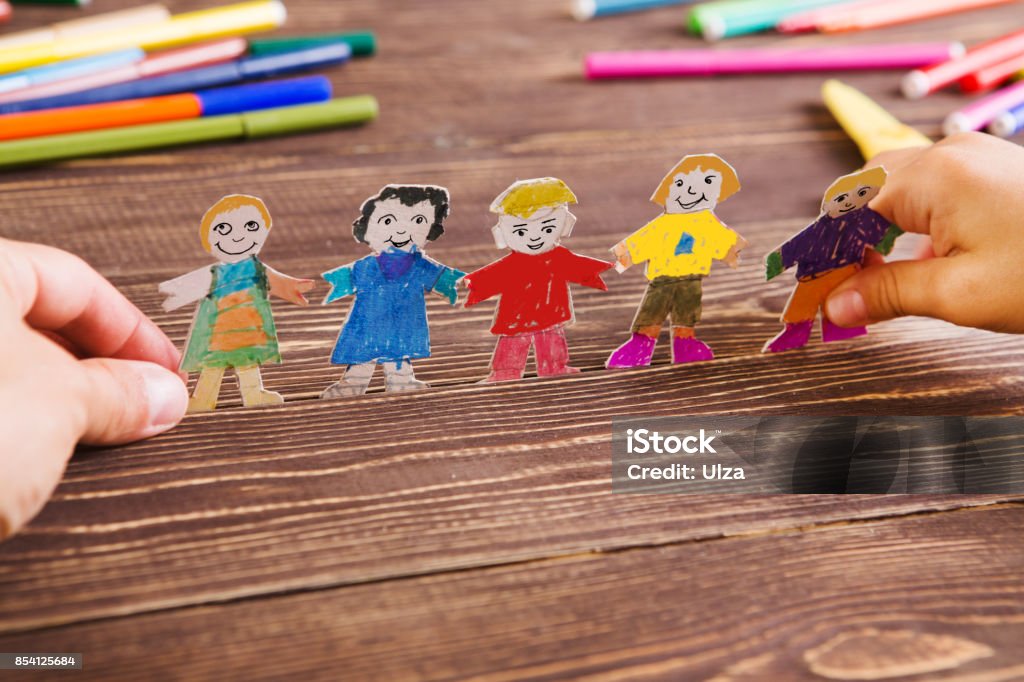 the child does figures of people of paper. Paper people on wooden background. Creative child play with craft. Preschool Stock Photo