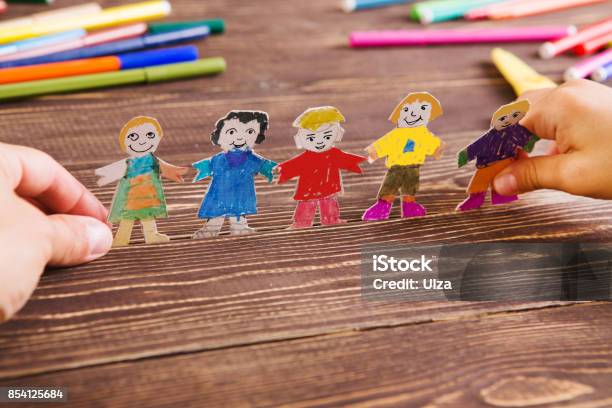 The Child Does Figures Of People Of Paper Paper People On Wooden Background Creative Child Play With Craft Stock Photo - Download Image Now