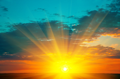 Beautiful blazing sunset landscape at over the meadow and orange sky above it. Amazing summer sunrise as a background.