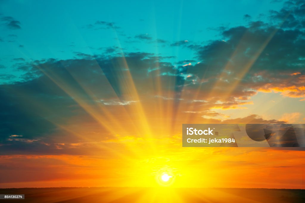 Beautiful blazing sunset landscape at over the meadow and orange sky above it. Amazing summer sunrise as a background. Sunrise - Dawn Stock Photo