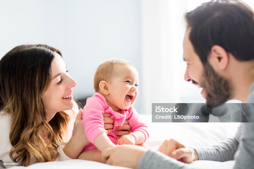 La mère de l’enfant père et son bébé sur un lit blanc - Photo de Bébé libre de droits