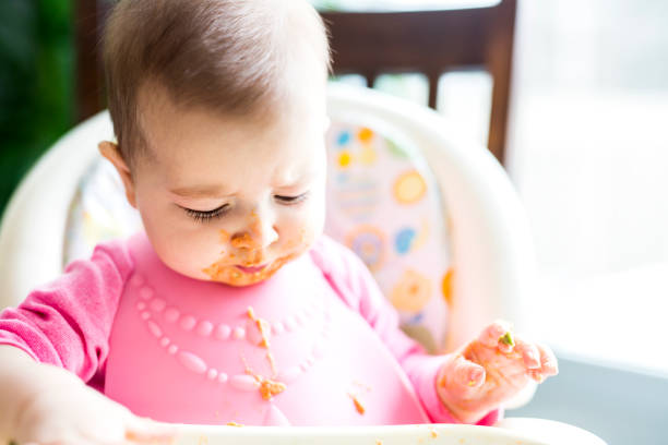 istock Adorable baby girl making a mess while feeding herself 854154774