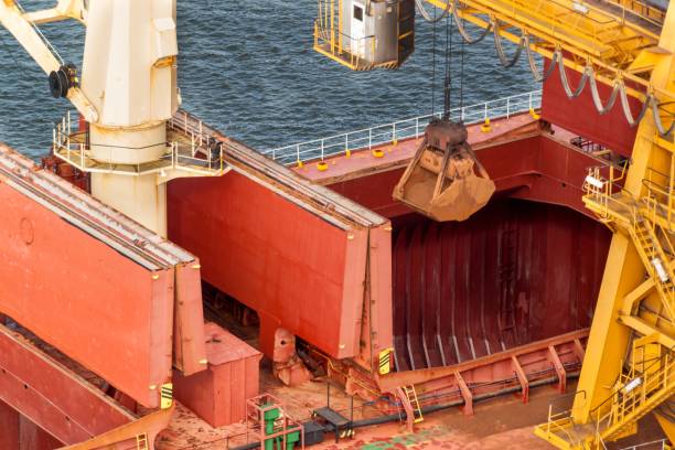 kran entlädt eisenerz am hafen. handel mit rohstoffen. arbeiten sie in einem hafen in der ostsee. - coal crane transportation cargo container stock-fotos und bilder