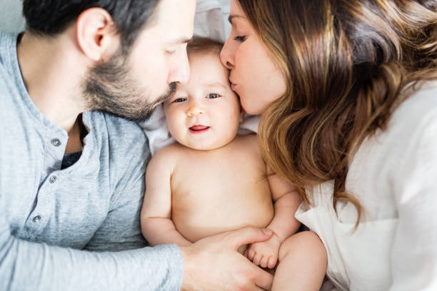 istock Mother father and baby child on a white bed 854155608