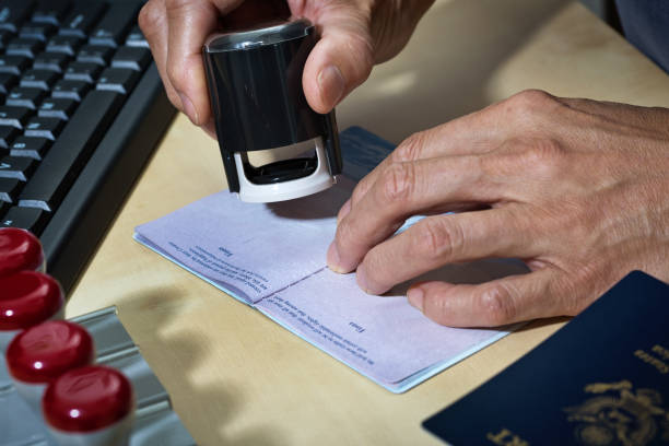 us border security, homeland security, pass prüfstation für einwanderung - customs official examining emigration and immigration document stock-fotos und bilder