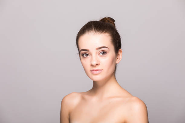 istock Beautiful woman face close up hand touching face studio on gray 854179346