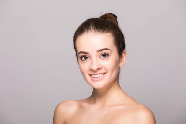 istock Beautiful woman face close up hand touching face studio on gray 854179478