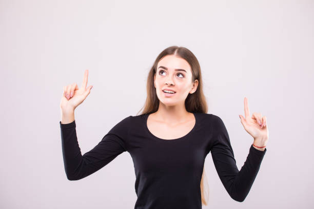 istock Beautiful young woman standing and pointing up over white background 854182870