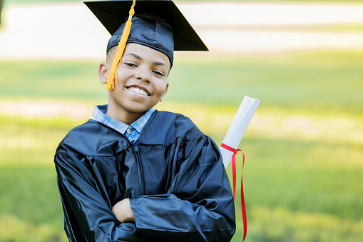 Handsome elementary school graduate smiles proudly after receiving his diploma.