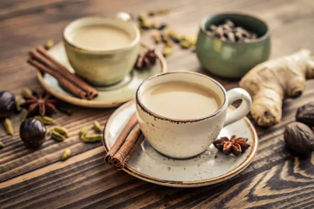Traditional indian drink - masala chai tea (milk tea) with spices on wooden background