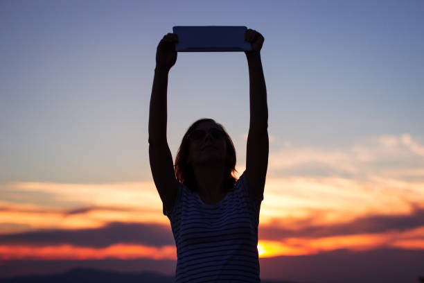 istock Woman watching sunset with a tablet 854211956