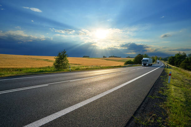 istock White trucks on the road at sunset with storm cloud 854219098