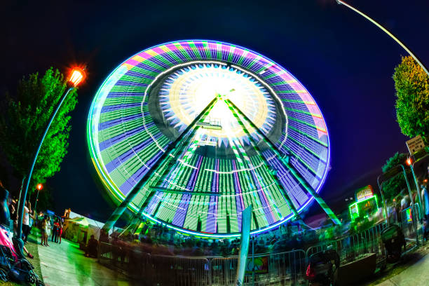 Falcon Heights, Minnesota, USA - September 3, 2017: Large Ferris Wheel Spinning and crowd wating to ride at dusk. Photo was taken at the Minnesota State Fair in Falcon Heights, Minnesota, with a fisheye lens. The MN State Fair is a 12 day annual event.