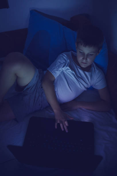 istock Young boy playing with laptop at night 854226104