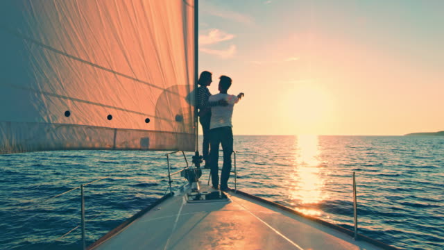 WS Couple pointing at the horizon from a sailboat at sunset