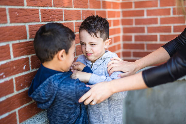 istock Teacher Stopping Two Boys Fighting In Playground 854244094