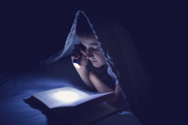 istock Little boy reading in the dark 854247032