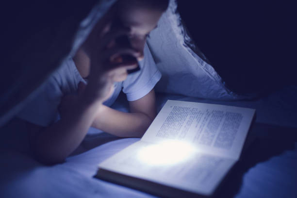 istock Little boy reading in the dark 854247352