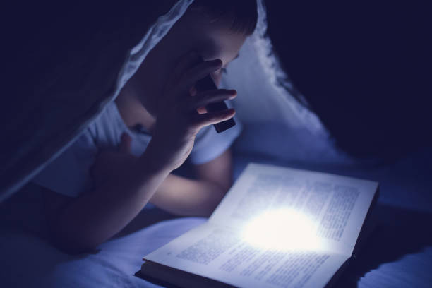 istock Little boy reading in the dark 854247514
